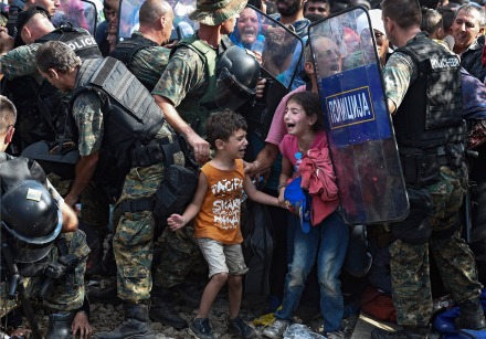 epaselect epa04891691 Children cry as migrants waiting on the Greek side of the border break through a cordon of Macedonian special police forces to cross into Macedonia, near the southern city of Gevgelija, The Former Yugoslav Republic of Macedonia, 21 August 2015. Macedonian police clashed with thousands of migrants attempting to break into the country after being stranded in no-man's land overnight, marking an escalation of the European refugee crisis for the Balkan country. EPA/GEORGI LICOVSKI